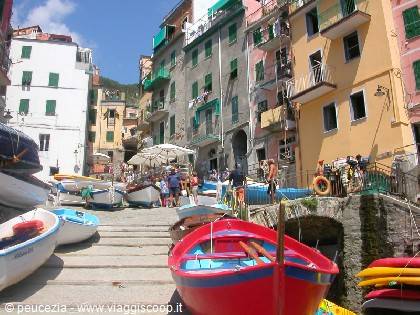Red boat moored among colorful houses and tourists on the ramp