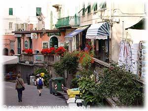 Ligurian village street with flowered balconies, striped awnings and passersby