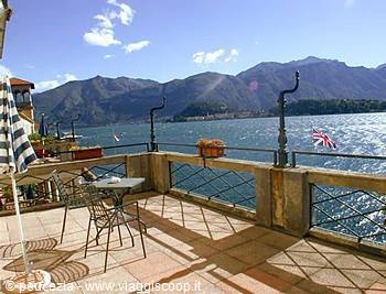 Terrace with table and chairs overlooking Lake Como, mountains behind
