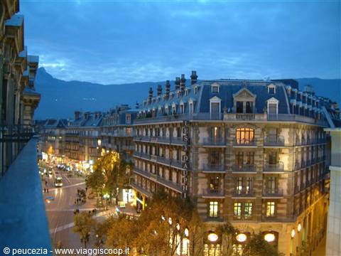 Grenoble at dusk: stone Haussmann buildings, lit windows, mountains behind