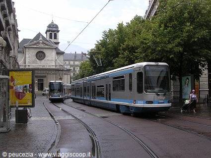 Blue and grey tram on wet tracks by the church, Geneva