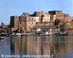 Aragonese Castle of Procida, ochre walls reflected on the sea, moored boats