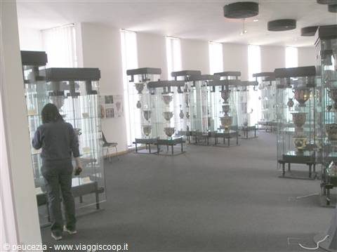 Visitor walking among glass display cases of ceramics in museum