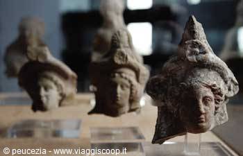 Terracotta female heads wearing helmets, ancient artifacts displayed in museum case