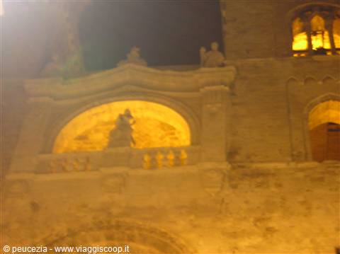 Stone church facade at night, illuminated niche with statue