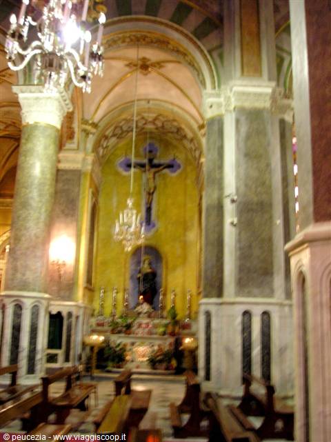 Church interior with altar, golden crucifix, marble columns and lit chandeliers