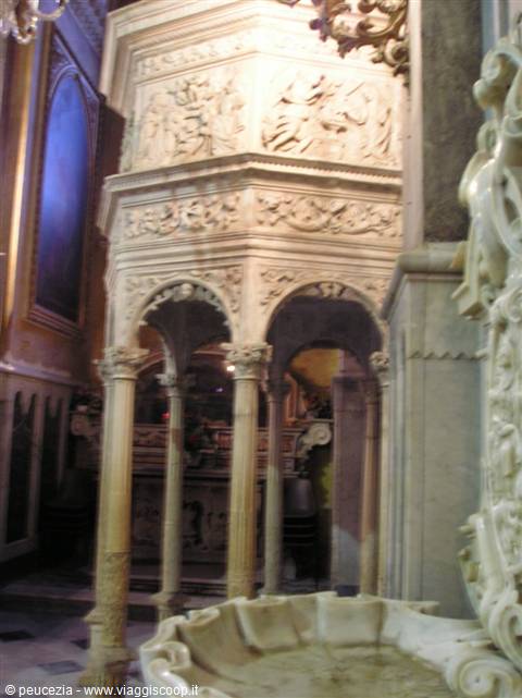 Carved marble pulpit with arches and columns inside a lit church
