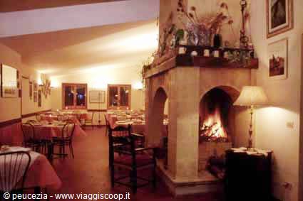 Restaurant dining room with lit stone fireplace, set tables and warm lamplight