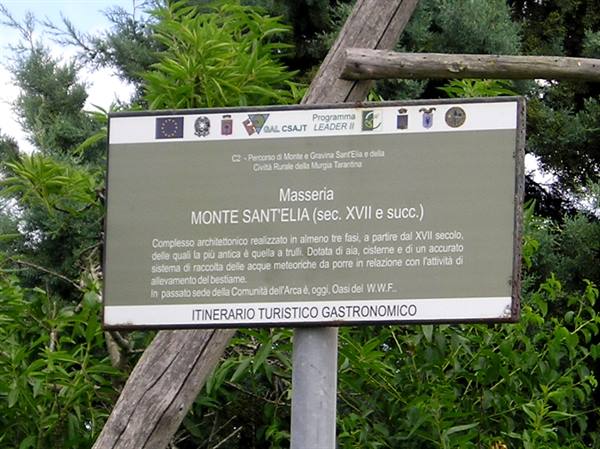 Tourist sign for Masseria Monte Sant'Elia among green trees