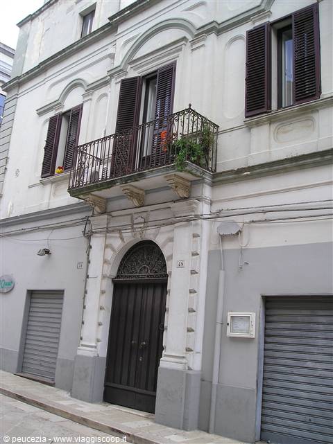 Building with wooden doorway, wrought iron balcony and brown shutters