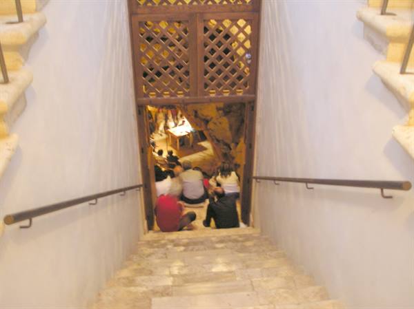 Stone staircase descending into a grotto, people seated below
