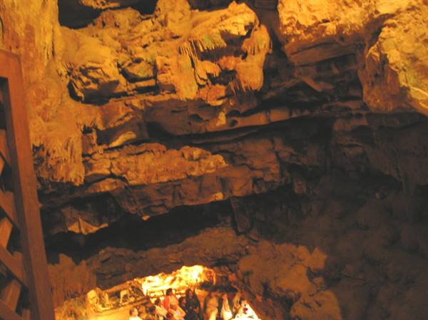 Tourists visit a cave with stalactites lit by golden light