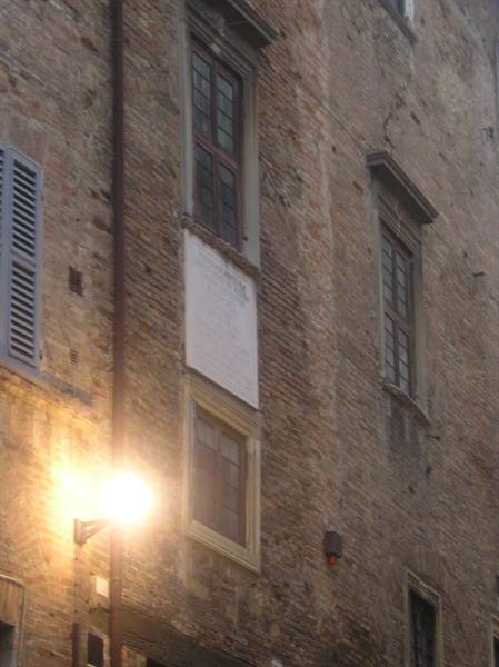Glowing street lamp against old brick facade with windows and white plaque