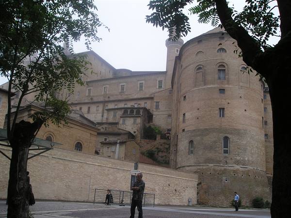 Ducal Palace of Urbino, round brick tower, man stands with crossed arms