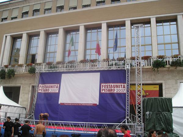 Blue FestaUnità Pesaro 2007 stage banner in front of building with flags