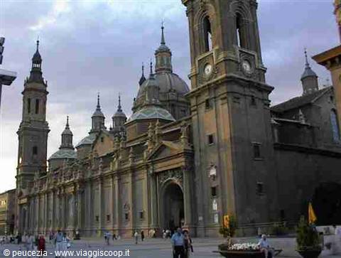 Basilica of Pilar in Zaragoza, towers and domes under cloudy sky, people walking