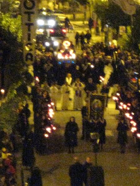 Night procession with candles, banner and statue amid the crowd