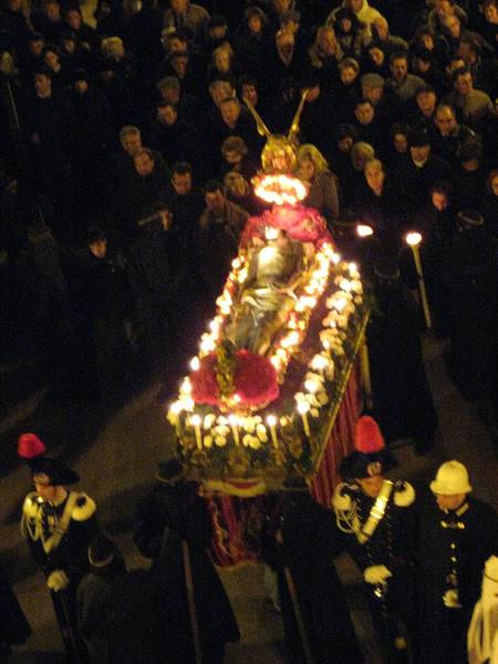 Night procession: saint's statue on candle-lit bier carried by Carabinieri