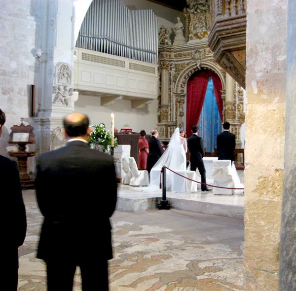 Bride in white dress before the gilded altar of a baroque church