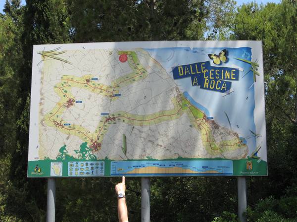 Hand pointing at the Dalle Cesine a Roca cycle trail map among trees