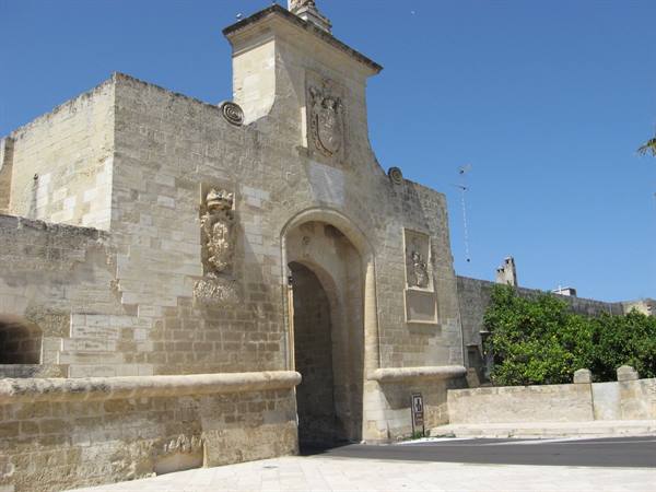 Monumental limestone gate with carved coats of arms, blue sky
