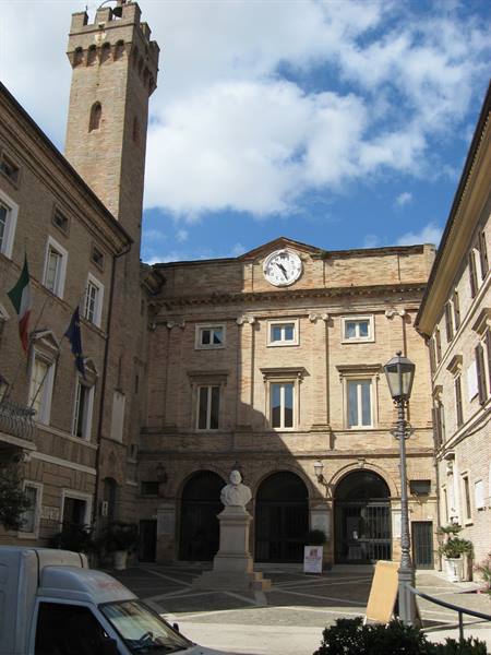 Square with brick town hall, medieval tower, marble bust and street lamp