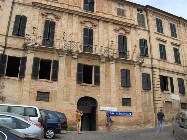 Tourists photograph the Galleria LIBERATI entrance with blue signs, ochre brick building
