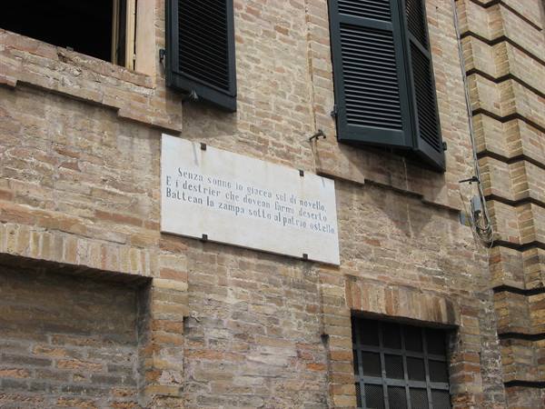 Marble plaque with verse on brick facade with green shutters