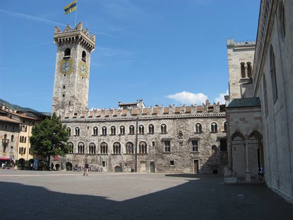 Piazza del Duomo in Trento: stone civic tower with clock and flag