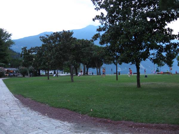 Lakeside park on Lake Garda with green lawns and hazy mountains