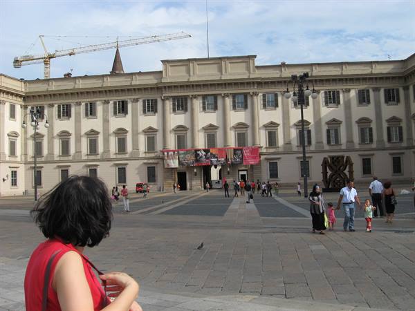 Tourist in front of Palazzo Reale in Milan, daylight, people walking in the square