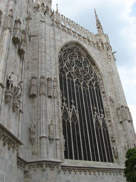 Marble facade of Milan Cathedral with Gothic rose window and statues