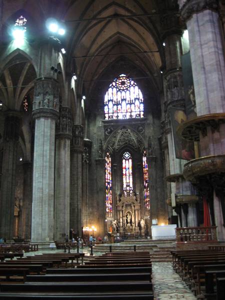 Naves and stained glass windows of Milan Cathedral, light filters among gothic columns