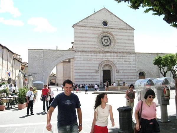 Tourists walk in front of the Basilica of Santa Chiara in Assisi, sunny day