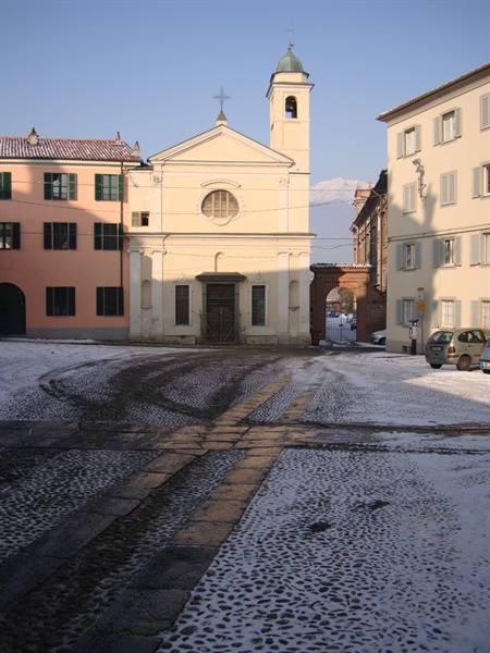 Yellow church with bell tower over snow-dusted cobblestone square