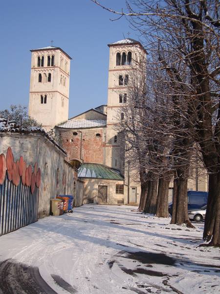 Church with two Romanesque towers among bare trees, snowy lane
