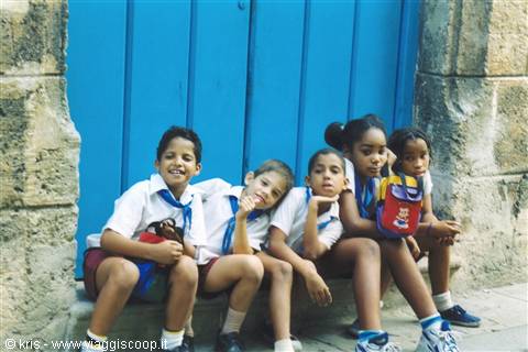 Schoolchildren in blue neckerchiefs sit in front of a large blue door
