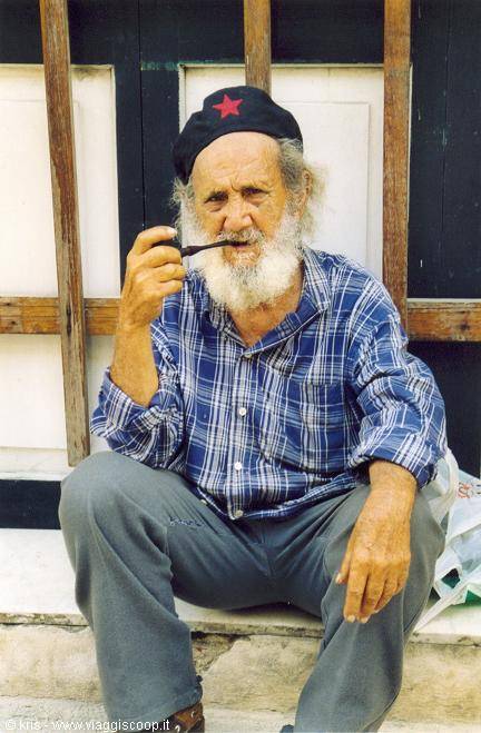 Old bearded man in red-star cap smoking a pipe