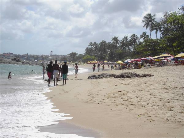 People walking along Morro de São Paulo beach under colorful umbrellas