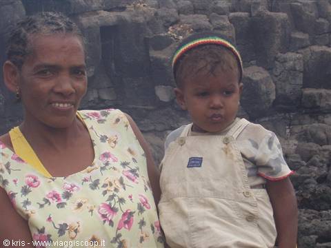 Mother and child in front of dark volcanic rock cliffs