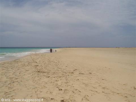 Walkers on golden sand by turquoise waves, Santa Maria, Sal