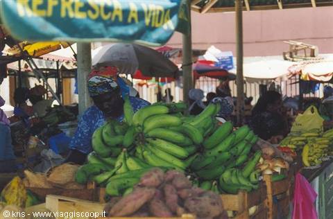 Woman at market stall with green bananas and colorful umbrellas, Refresca a Vida sign