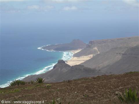 Arid cliffs over the ocean with sandy beach and white breaking waves