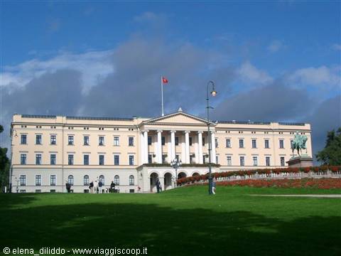 The Royal Palace in Oslo, yellow facade with columns, green lawns and pedestrians