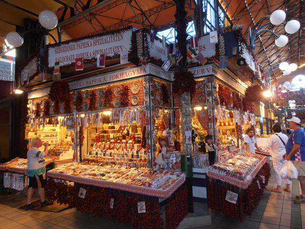 Paprika stall in Budapest's Great Market Hall, tourists among hanging chili garlands