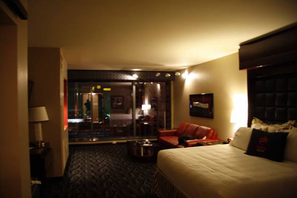 Dim hotel room with warm lamps, red sofa and windows over Las Vegas