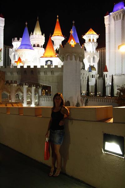 Woman with red bag in front of the illuminated Excalibur castle at night