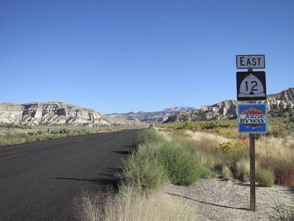 East 12 Scenic Byway sign beside asphalt road, rocky mountains