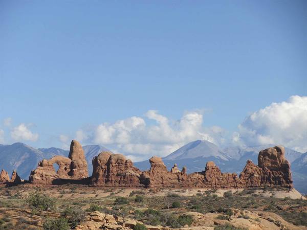 Red sandstone fins and arches at Arches National Park, mountains and clouds behind