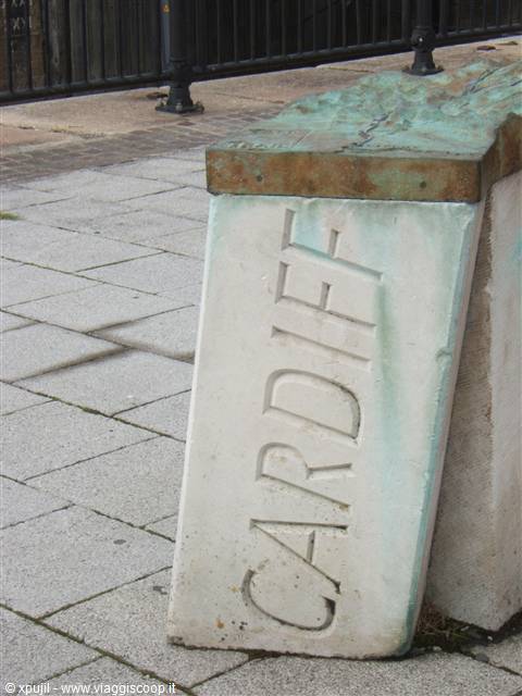 Stone block engraved with Cardiff, resting on grey paved ground